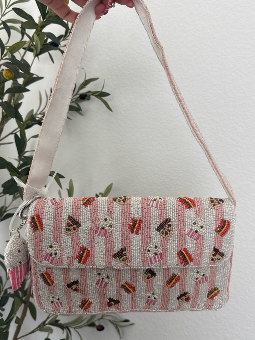 Pink beaded crossbody bag with repeating pattern of cupcakes and striped boxes